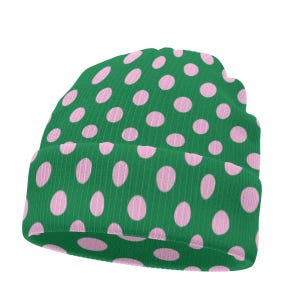 Puede incluir: Un gorro de punto acanalado en un color verde vibrante con un patrón repetitivo de lunares de color rosa claro. El gorro tiene un dobladillo plegado en la parte inferior y una corona redondeada, hecho de tela texturizada con canalé vertical.