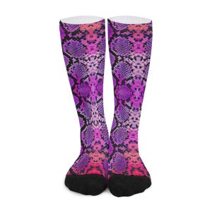 Puede incluir: Un par de calcetines de media caña con un vibrante estampado de piel de serpiente en tonos rosa brillante, morado y negro. El diseño cubre toda la caña de los calcetines, con tejido negro sólido en la puntera y el talón para crear contraste.