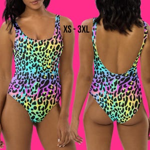 May include: A one-piece swimsuit featuring a vibrant, multi-colored leopard print pattern in shades of yellow, blue, purple, and pink. The garment has a scoop neckline and a low-cut back design. The text XS - 3XL is printed on the image.