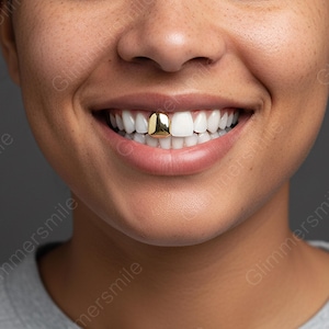Può includere: Primo piano di una persona sorridente, che mostra denti bianchi e un dente d'oro. Il dente d'oro è di forma quadrata e lucente, in contrasto con i denti naturali. La pelle è liscia e lo sfondo è grigio.
