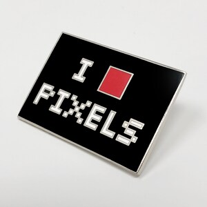 May include: Black enamel pin with a white pixelated 'I ♥ PIXELS' design. The heart is a red pixel.