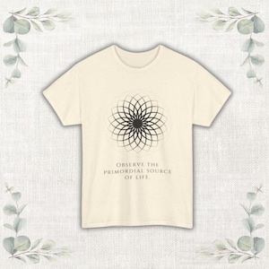 May include: Cream-colored t-shirt featuring a black geometric design and the text "OBSERVE THE PRIMORDIAL SOURCE OF LIFE." The design is a symmetrical pattern of curved lines radiating from a central point. The shirt has short sleeves and a crew neck.