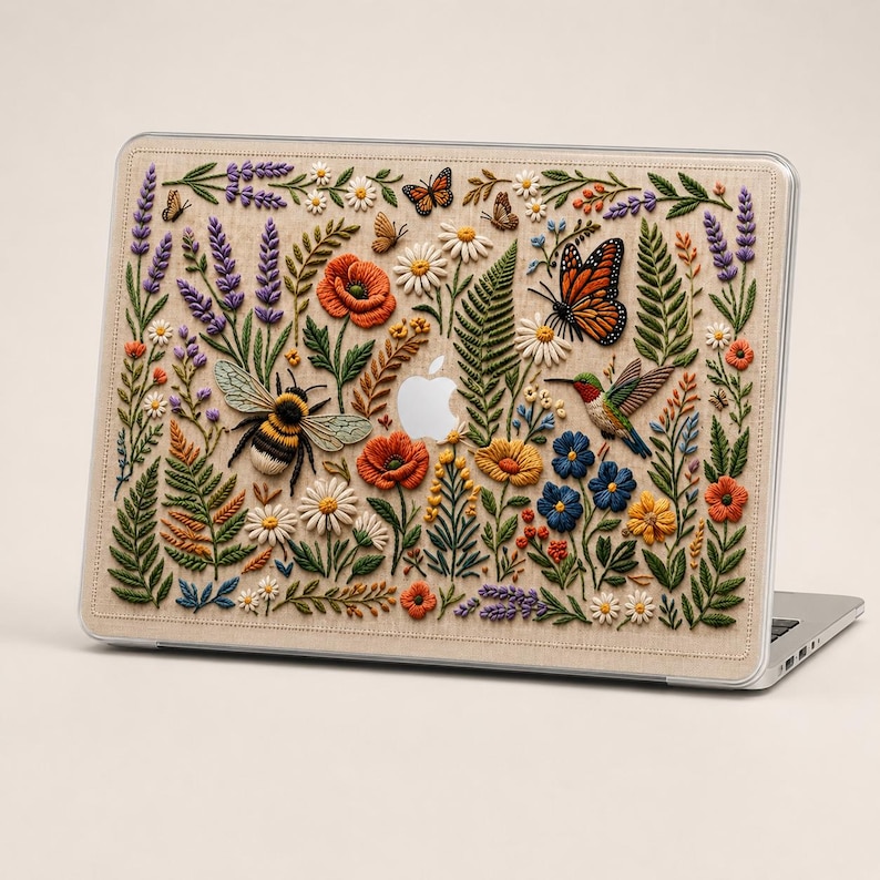 MacBook case with floral embroidery effect design featuring detailed wildflowers, lavender, poppies, ferns, daisies, monarch butterfly, hummingbird, and bumblebee on warm linen-texture background. Rich botanical illustration in greens, reds, purples, and yellows. Clean product view showing full case coverage and precise fit on MacBook. Cottagecore nature-inspired aesthetic for women who love botanical art and vintage embroidery style.