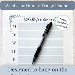 May include: A white paper fridge planner with the text What's for dinner? and days of the week M, Tu, W, Th, F listed vertically. It features a blue floral corner design and a black retractable pen resting on the page. A circular badge reads Instant Digital PDF Download.