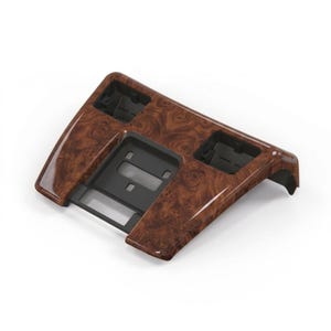 Puede incluir: Un embellecedor interior de coche con acabado brillante de veta de madera. El embellecedor es principalmente marrón con patrones oscuros. Tiene forma rectangular con huecos para varios componentes.