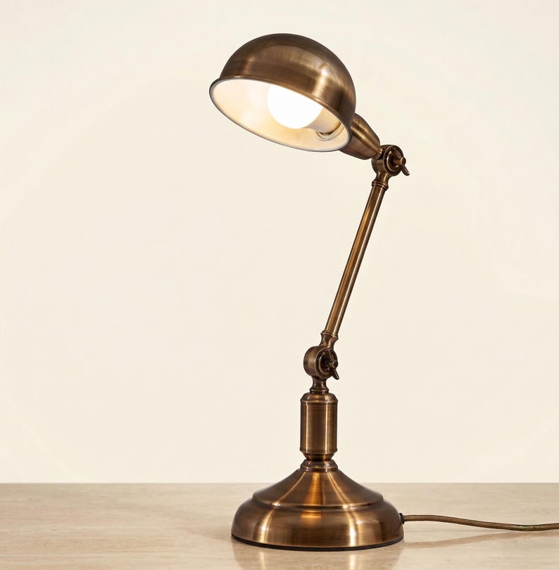 Antique brass table lamp with adjustable head on a clean neutral background