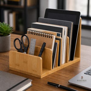 May include: A bamboo desk organizer with multiple compartments. It holds notebooks, a tablet, pens, scissors, and a ruler. The organizer is on a wooden desk, with a laptop and a small plant in the background. The text "ROSETREE ORGANIZER" is visible.