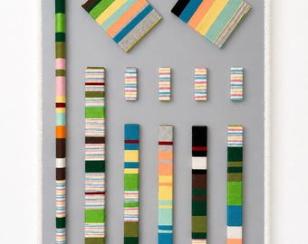 May include: An abstract composition featuring various rectangular and cylindrical forms with colorful striped patterns. The arrangement includes two square pieces and several vertical columns, showcasing a diverse palette of colors like green, blue, and pink.