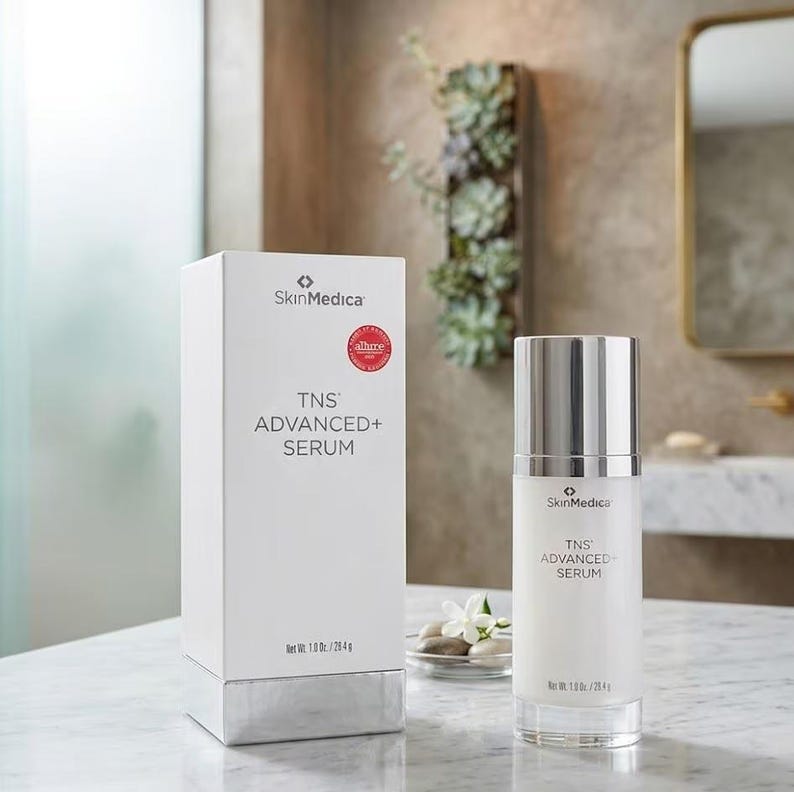 May include: A white rectangular box and a cylindrical bottle of SkinMedica TNS ADVANCED+ SERUM. Both items feature the brand name, product title, and a net weight of 1.0 oz / 28.4 g. The bottle has a metallic silver cap and a clear base.