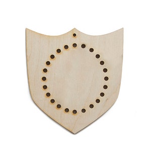 May include: Wooden shield-shaped craft blank with a circle of holes for weaving or stitching.