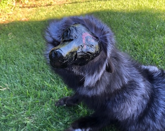 Puede incluir: Una figura de animal de peluche con pelo sintético largo y oscuro con puntas plateadas y una máscara moldeada de color negro brillante que cubre la cara. La máscara tiene una textura suave e irregular con una pequeña marca roja lateral.