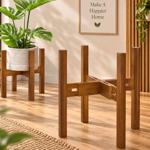 May include: A brown wooden plant stand with a cross-shaped base and four vertical legs. The stand features an adjustable design with interlocking joints, allowing it to accommodate various pot sizes. The structure is made of smooth wood.