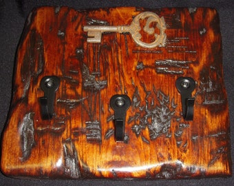 Porta-chaves rústico em madeira de cedro, com detalhes em ferro forjado, ideal para decoração de hall de entrada.