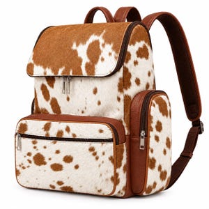 May include: A backpack featuring a brown and white cow print pattern with a textured hair-on-hide appearance. The bag includes a top flap, a large front zippered pocket, side pockets, and brown leather-like trim with silver-toned metal zippers.