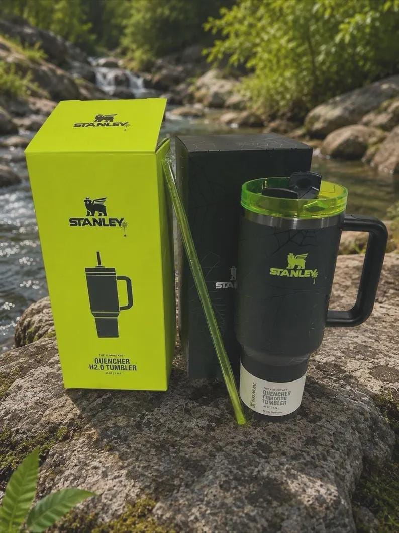 Puede incluir: Un vaso Stanley Quencher H2.0 negro mate con tapa y asa de color verde ne&oacute;n, acompa&ntilde;ado de una pajita verde ne&oacute;n a juego. El vaso se muestra junto a su caja de producto de color verde ne&oacute;n brillante y una caja negra, con el logotipo de Stanley.