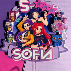 Puede incluir: Adorno de pastel de cumpleaños morado y rosa con el nombre "SOFIA" en letras blancas grandes. El adorno presenta ilustraciones de dibujos animados de chicas, estrellas y el número "5". También se incluye un gato azul.