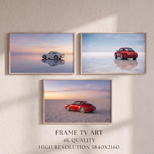 May include: Three rectangular framed wall art prints featuring sports cars. The top left shows a white car on a reflective surface at sunset. The top right shows a red car on a reflective surface. The bottom shows a red car on cracked earth.