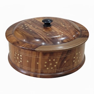 May include: A round wooden box with a lid. The box is made of dark brown wood with a natural grain pattern. The lid has a black knob and is decorated with inlaid star and dot patterns. The sides of the box also feature inlaid star and dot patterns.