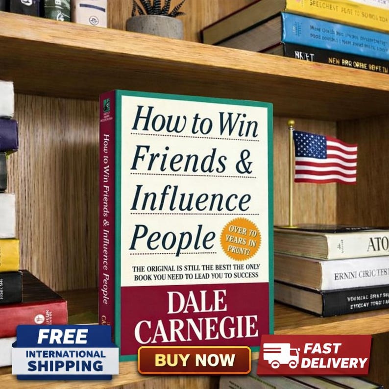 May include: A copy of "How to Win Friends & Influence People" by Dale Carnegie, displayed on a wooden shelf. The book has a green and red cover with the title in large black letters. An American flag is displayed next to the book.