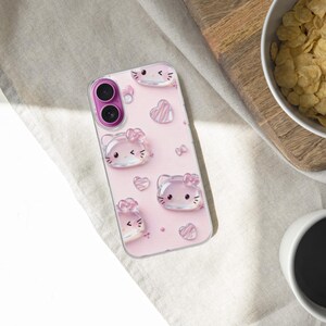 May include: A clear smartphone case with a light pink background featuring a repeating pattern of translucent, glossy cat faces with bows and small hearts. The case has a circular cutout for a dual-lens camera system with a bright magenta border.
