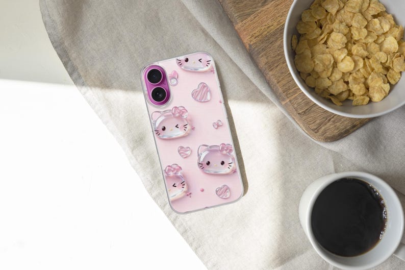 May include: A clear smartphone case with a light pink background featuring a repeating pattern of translucent, glossy cat faces with bows and small hearts. The case has a circular cutout for a dual-lens camera system with a bright magenta border.