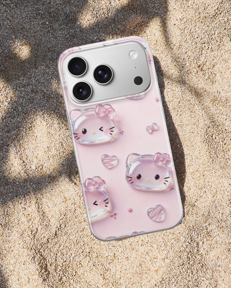 May include: A clear smartphone case featuring a light pink background with raised, translucent 3D-style cat faces, small bows, and heart shapes. The case has a cutout for a triple-lens camera system and is designed to fit a modern mobile device.