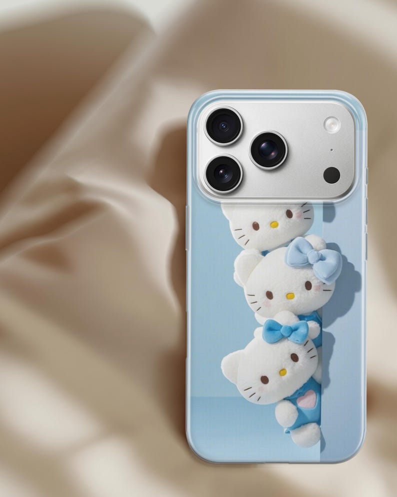 May include: A clear smartphone case featuring a light blue background with three stacked white Hello Kitty figures. Each figure has a yellow nose, black eyes, and whiskers. Two of the figures wear light blue bows, and one wears a blue outfit.