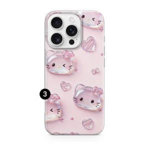 May include: A light pink smartphone case featuring a repeating pattern of translucent, 3D-style Hello Kitty character faces and small hearts. The design includes a black number 3 in a circle on the left side and a camera cutout at the top.