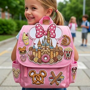 May include: Pink backpack featuring a Minnie Mouse bow and castle design. The backpack is adorned with food-themed patches, including a burger, donut, popcorn, and ice cream. It has two side pockets and a top handle.