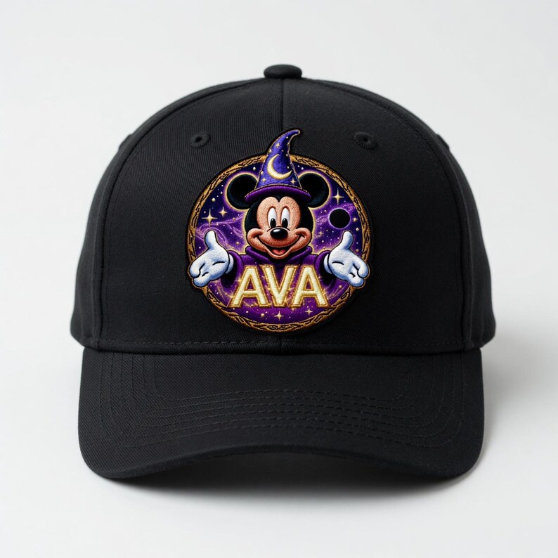 May include: Black baseball cap featuring a circular patch with Mickey Mouse dressed as a wizard. The patch includes the name "AVA" in gold lettering, a purple and gold border, and a starry background. The cap has a curved brim.