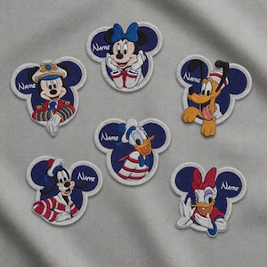 Peut inclure: Écussons brodés représentant des personnages Disney dans la forme de la tête de Mickey Mouse. Les personnages incluent Mickey, Minnie, Donald, Daisy, Dingo et Pluto. Chaque écusson a une bordure bleue et un espace pour un nom.