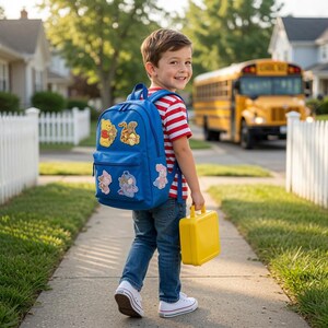 May include: A bright blue backpack featuring embroidered patches of Winnie the Pooh characters, including Pooh, Tigger, Piglet, and Eeyore. The backpack has a main compartment and a front zippered pocket, paired with a solid yellow rectangular lunch box.