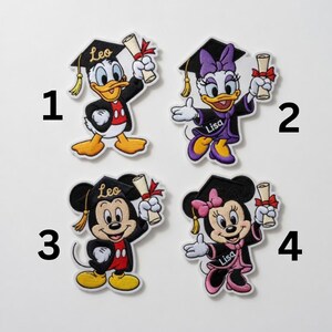 Puede incluir: Cuatro parches bordados con personajes de dibujos animados con atuendo de graduaci&oacute;n. Donald Duck, Mickey Mouse, Daisy Duck y Minnie Mouse est&aacute;n representados con gorros de graduaci&oacute;n y diplomas. Cada parche tiene un nombre en la gorra o la toga.