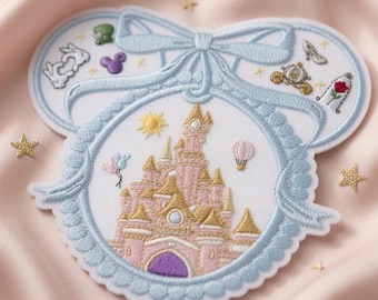 May include: A white embroidered patch shaped like mouse ears with a light blue ribbon border. The center features a pink and gold castle, a yellow sun, and a hot air balloon. Smaller embroidered icons include a white rabbit, a glass slipper, a carriage, and a rose.