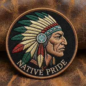 Könnte beinhalten: Runder, gestickter Aufnäher mit einem indianischen Häuptling im Profil, der einen Federkopfschmuck mit roten, grünen und gelben Akzenten trägt. Der Aufnäher trägt die weißen Worte "NATIVE PRIDE" auf schwarzem Grund.