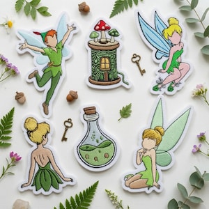 May include: A collection of embroidered patches featuring a flying boy in green, a fairy with blue wings, a fairy with green wings, a fairy seen from behind, a mushroom house on a spool, and a potion bottle, accompanied by two small metal keys.