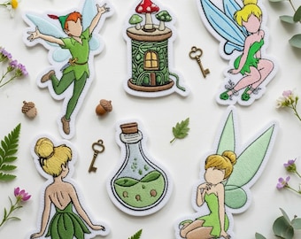 May include: A collection of embroidered patches featuring a flying boy in green, a fairy with blue wings, a fairy with green wings, a fairy seen from behind, a mushroom house on a spool, and a potion bottle, accompanied by two small metal keys.