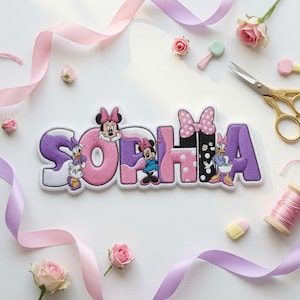 May include: An embroidered name patch featuring the name SOPHIA in a stylized font with purple, pink, and black colors. The design incorporates cartoon characters including Minnie Mouse and Daisy Duck, along with polka dot patterns and bows.