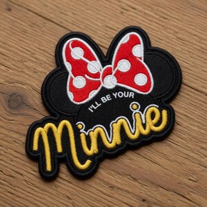 May include: Embroidered patch featuring a black Minnie Mouse silhouette with a red bow with white polka dots. The patch includes the text "I'll be your Minnie" in yellow script.