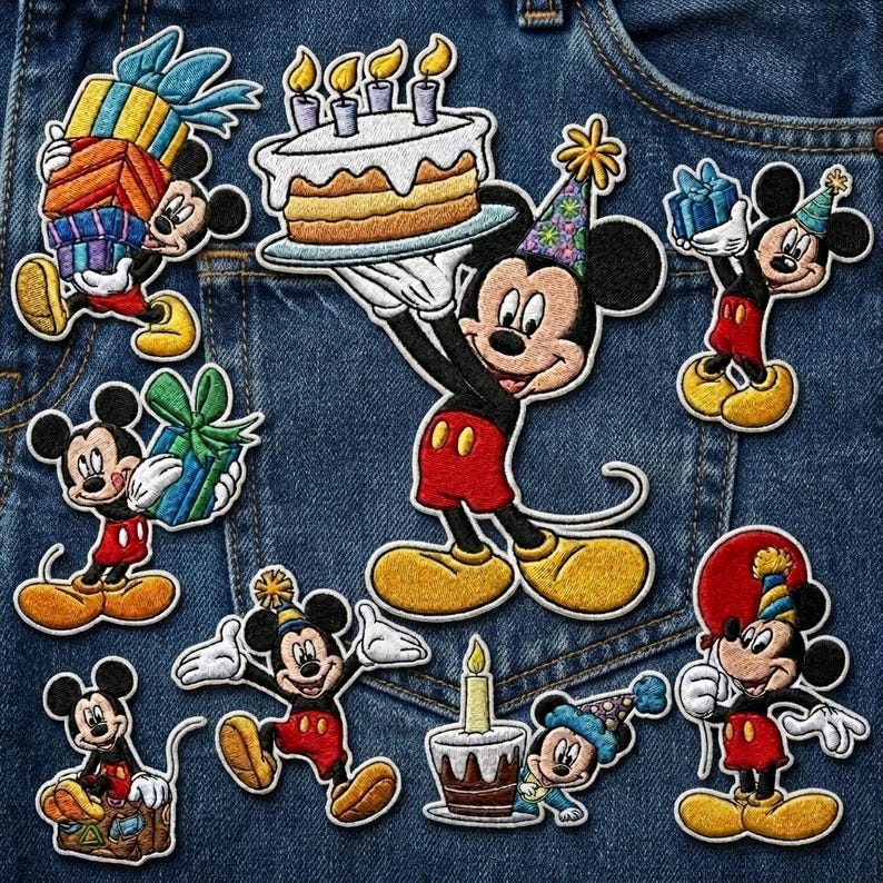 May include: A collection of embroidered Mickey Mouse patches in various poses, celebrating a birthday. Mickey is holding gifts, a cake with candles, and a balloon. The patches are in red, black, yellow, and white, with blue and green accents, set against a denim background.