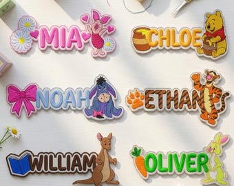 May include: Six embroidered name patches featuring Winnie the Pooh characters. The names Mia, Chloe, Noah, Ethan, William, and Oliver are displayed alongside Piglet, Pooh, Eeyore, Tigger, Roo, and Rabbit with associated icons like flowers, honey, bows, and carrots.