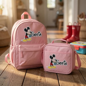 May include: A pink backpack and a matching pink lunch bag, both featuring a graphic of Mickey Mouse holding books and the name Sofia printed in black. The lunch bag has a subtle white polka dot pattern and a top handle with an adjustable strap.