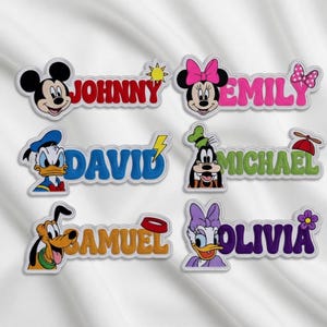 May include: Embroidered name patches featuring Disney characters Mickey Mouse, Minnie Mouse, Donald Duck, Goofy, Pluto, and Daisy Duck. Each patch has a name in a different color, such as red, pink, blue, green, orange, and purple.