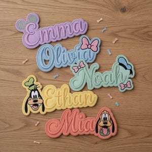 May include: Embroidered name patches in pastel colors, featuring names like Emma, Olivia, Noah, Ethan, and Mia. Each patch has a unique design, with some incorporating cartoon character elements like Mickey Mouse ears, bows, and character faces.