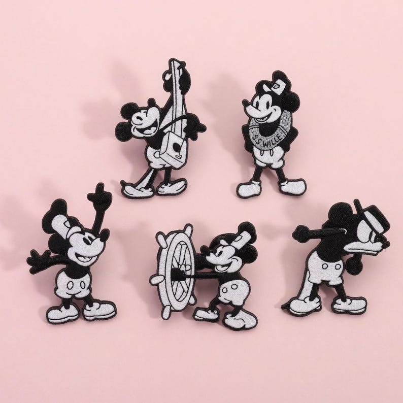 Op de afbeelding: Set van vijf zwart-witte geborduurde patches met Mickey Mouse in verschillende poses. E&eacute;n patch toont Mickey die een snaarinstrument bespeelt, een andere met een scheepsstuur, en andere in speelse houdingen. Op een lichtroze achtergrond.