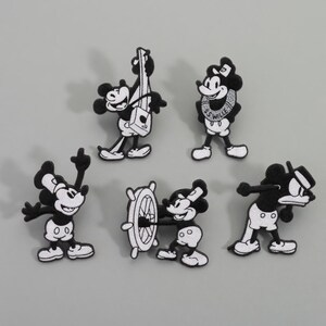 Op de afbeelding: Set van vijf zwart-witte geborduurde patches met een cartoonmuis in verschillende poses. E&eacute;n patch toont de muis die een snaarinstrument bespeelt, een andere aan een scheepsstuurwiel en een derde met een matrozenkraag.