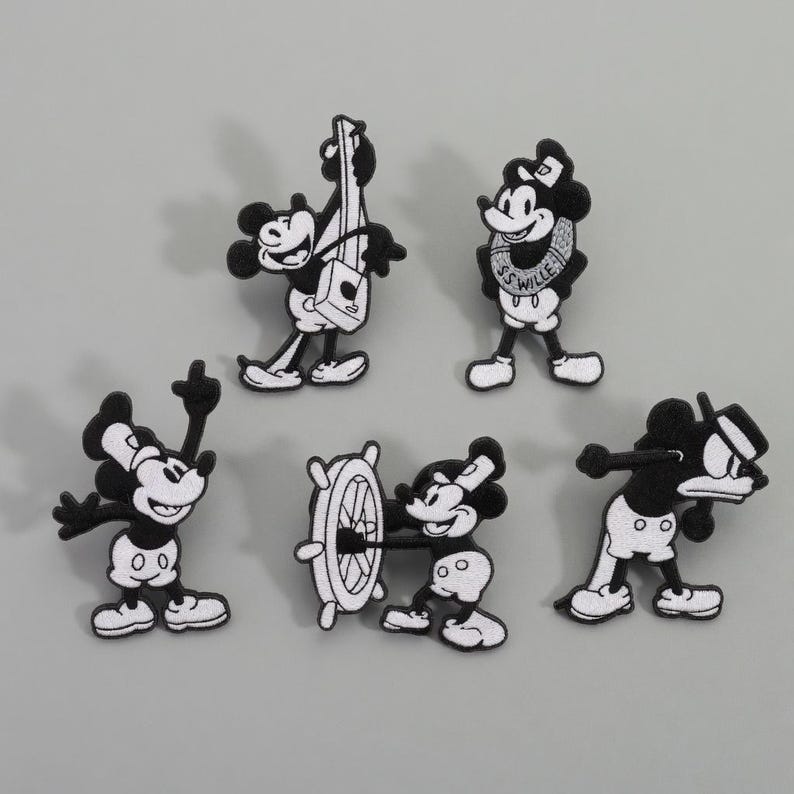 Op de afbeelding: Set van vijf zwart-witte geborduurde patches met een cartoonmuis in verschillende poses. E&eacute;n patch toont de muis die een snaarinstrument bespeelt, een andere aan een scheepsstuurwiel en een derde met een matrozenkraag.