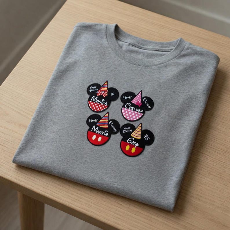 以下が含まれることがあります： ミッキーマウスをモチーフにした4つの誕生日デザインが施されたグレーのTシャツ。各デザインには、マウスの頭、パーティーハット、「Happy Birthday」の文字が含まれています。「Monica」、「Chelsea」、「Martin」、「Garp」の名前が表示されています。