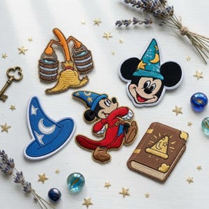 May include: A collection of embroidered patches featuring a broom carrying two buckets, a Mickey Mouse head in a blue wizard hat, a blue wizard hat, a full-body Mickey Mouse in a red robe and blue hat, and a brown spellbook with a gold hat icon.