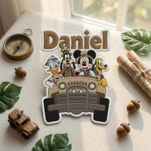 Puede incluir: Un parche bordado personalizado con el nombre Daniel en letras marrones sobre un jeep color canela que lleva a Mickey Mouse, el Pato Donald, Goofy y Pluto con ropa de safari. Los personajes están representados en estilo caricatura con costuras.